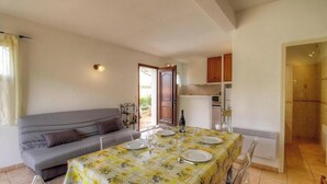A dining area with a table set for four, a sofa, and a kitchen in the background. - Francesca - SOTTA - Gîte (SOTTA)
