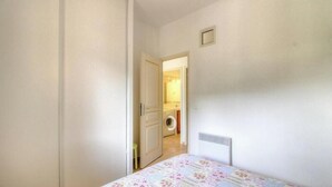 A narrow hallway leading to a room with a bed, a radiator, and a door to a laundry area. - Francesca - SOTTA - Gîte (SOTTA)