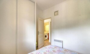 A narrow hallway leading to a room with a bed, a radiator, and a door to a laundry area. - Francesca - SOTTA - Gîte (SOTTA)