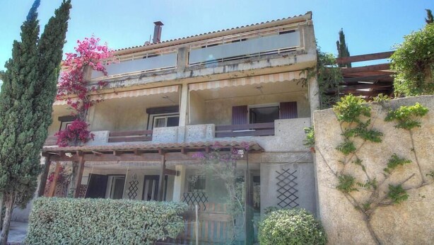 A two-story building with balconies, a stone facade, and a garden area with shrubs and a tree. - MIMOSA 3 - PORTO POLLO (PORTO POLLO)