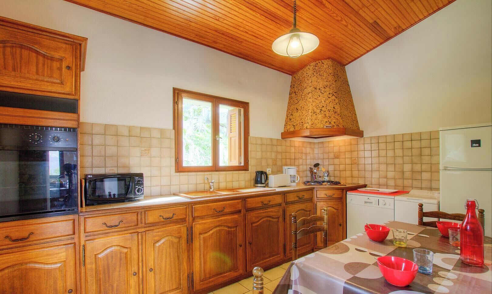 A kitchen with wooden cabinets, a stove, microwave, and a window.