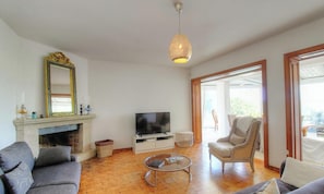 A living room with a fireplace, television, sofa, armchair, and a hanging light fixture. - Casa Chjarina - SOTTA (SOTTA)