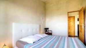 A bedroom with a bed, a chair, and a wooden door. - I Pinzzelli 2 - FARINOLE (FARINOLE)