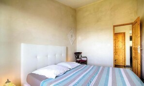 A bedroom with a bed, a chair, and a wooden door. - I Pinzzelli 2 - FARINOLE (FARINOLE)
