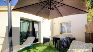 A patio with a table and chairs, a lounge chair, and a large umbrella. - I Pinzzelli 2 - FARINOLE (FARINOLE)