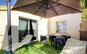 A patio with a table and chairs, a lounge chair, and a large umbrella. - I Pinzzelli 2 - FARINOLE (FARINOLE)