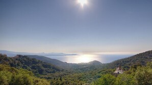 A coastal landscape with a clear sky, a body of water, and a hill with a structure. - I Pinzzelli 2 - FARINOLE (FARINOLE)