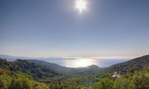 A coastal landscape with a clear sky, a body of water, and a hill with a structure. - I Pinzzelli 2 - FARINOLE (FARINOLE)