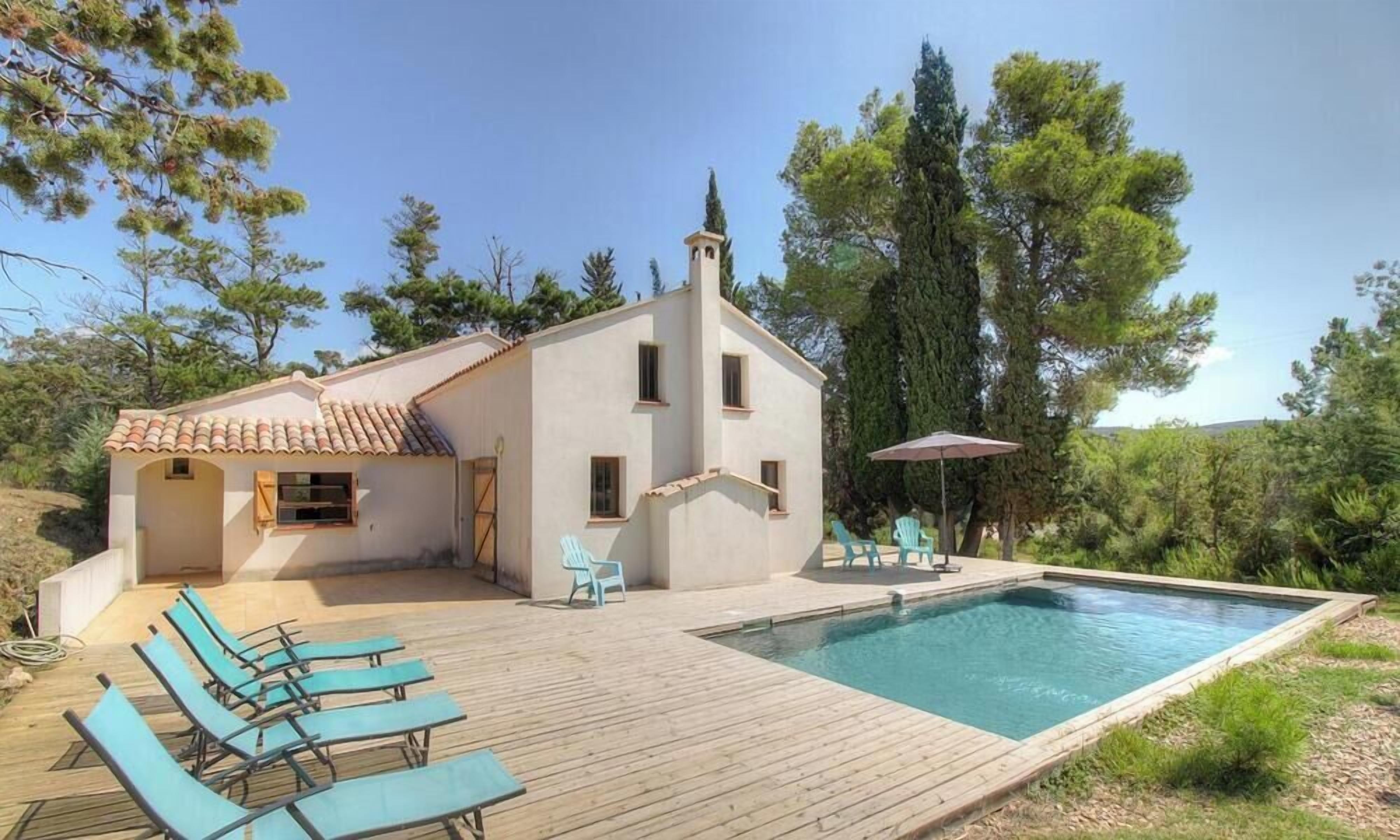 Une maison avec une piscine, un espace salon extérieur et une pergola.