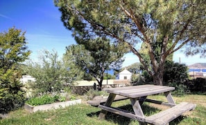A picnic table in a grassy area with trees and a view of buildings in the background. - ARIA MARINA 2 - GALERIA (GALERIA)