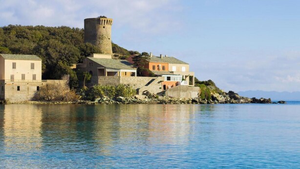 A coastal town with a historic tower, stone buildings, and a calm sea. - Casa Meria 1 - MERIA (MERIA)