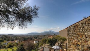 Edificio de piedra con vistas a montañas y un jardín.