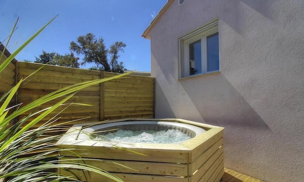 Ein hölzernes Whirlpool im Garten mit einem Haus im Hintergrund.