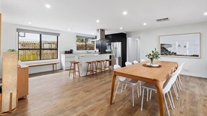 Una cocina moderna con una isla central, armarios blancos y electrodomésticos de acero inoxidable.