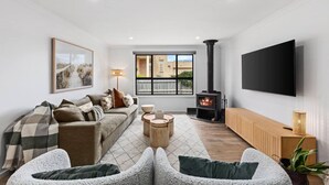 Una sala de estar moderna con sofá, una mesa de centro, televisión, chimenea y ventana con vistas.