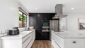 Una cocina moderna con armarios blancos, horno empotrado y refrigerador de acero inoxidable.