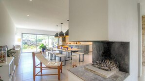 Eine moderne Küche mit einer großen Kochinsel, Pendelleuchten und einem Kamin.