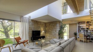 Ein geräumiges Wohnzimmer mit Steinsandsteinwand, einem Flachbildfernseher, einem Sofa, einem Couchtisch und einem Bücherregal.