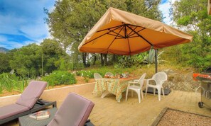An outdoor patio with a table, chairs, and a grill. - L'alivetu - PERI - Gîte (PERI)