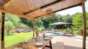 Uma área de refeições externa com um deque de madeira, piscina e um espaço de estar coberto.