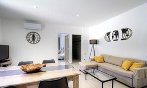A modern living room with a dining table, sofa, and a television. - A Fabrica - CATERI - Guest house (CATERI)