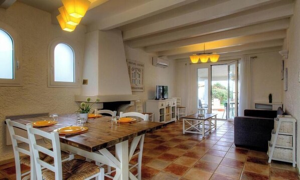 A spacious dining area with a wooden table, white chairs, and a view of the outdoors.