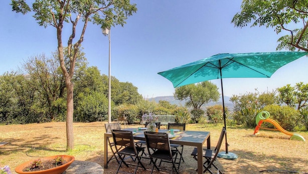 An outdoor dining area with a table and chairs, a large umbrella, and a playground structure. - A Muvra - AJACCIO - Gîte (AJACCIO)