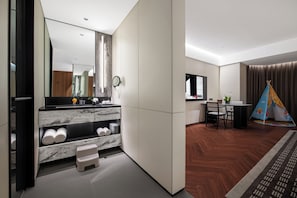 A modern hotel room with a large mirror, a wooden vanity, a small stool, a dining area with a table and chairs, and a colorful teepee decoration. - Intercity Hotel WeiHai Torch Eighth St. (Weihai)