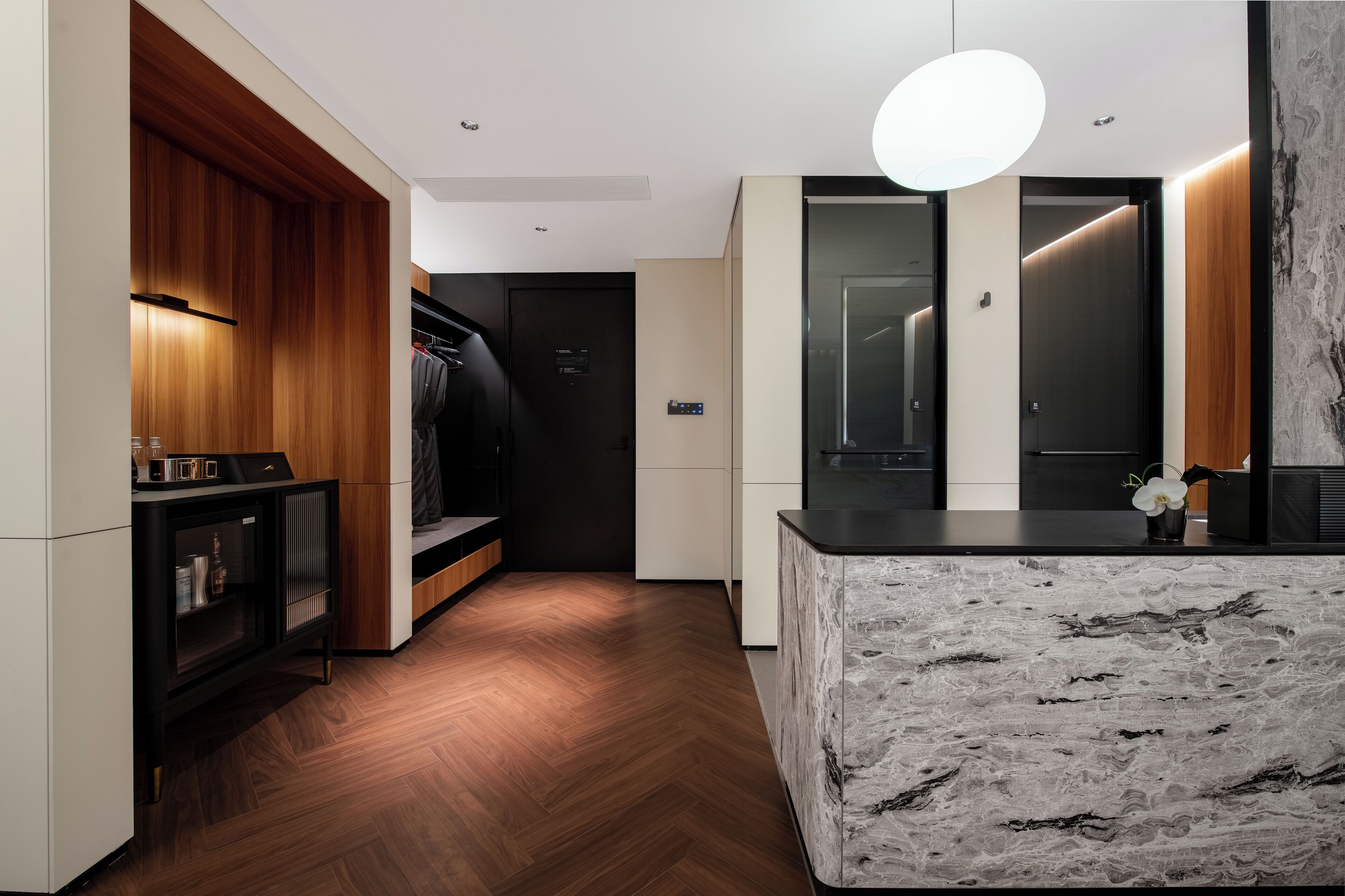 A modern kitchen with a marble countertop, wooden cabinets, and a black hanging rack.