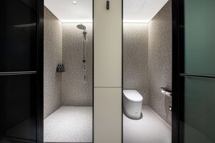 Un baño moderno con ducha, inodoro y armario de almacenamiento.