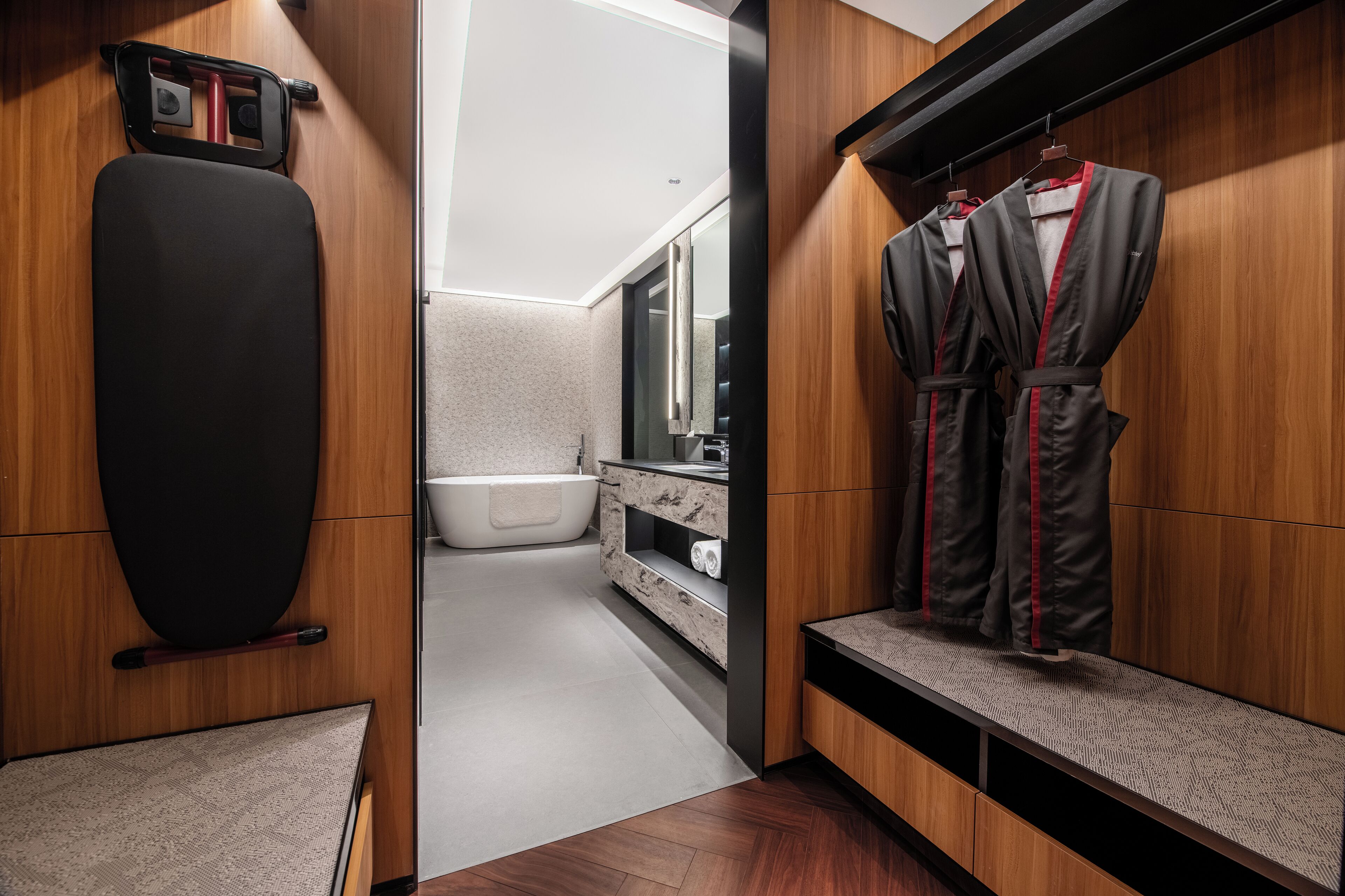 A modern bathroom with a wooden vanity, a black exercise ball, a bathtub, and a robe rack.