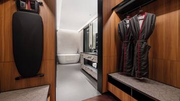 A modern bathroom with a wooden vanity, a black exercise ball, a bathtub, and a robe rack.
