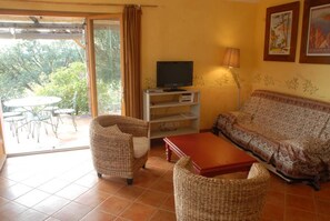 A living room with wicker furniture, a television, and a sofa. - Myrtle - MONACIA D'AULLENE (MONACIA D'AULLENE)