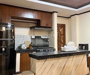 Una cocina con gabinetes de madera, un refrigerador de acero inoxidable, una estufa a gas y un horno empotrado.