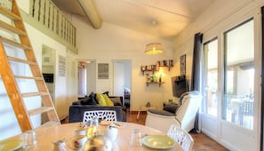 Ein Wohnzimmer mit Esstisch, einer Couch, einem Fernseher und einer Treppe.