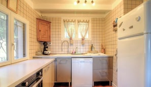 Eine kleine Küche mit Geschirrspüler, Kaffeemaschine und Kühlschrank.