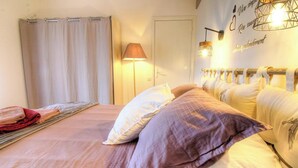 A bedroom with a bed, curtains, a lamp, and a wall with decorative text. - In Castiniccia - CASAGLIONE (CASAGLIONE)