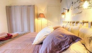Ein Schlafzimmer mit Bett, Vorhängen, einer Lampe und einer Wand mit dekorativem Text.