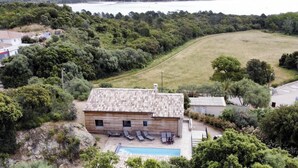 Et hus med swimmingpool, omgivet af træer og havudsigt.