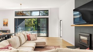 A modern living room with a sectional sofa, a fireplace, and a large sliding glass door leading to a balcony.