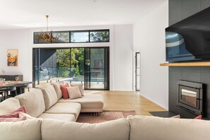 A modern living room with a sectional sofa, a fireplace, and a large sliding glass door leading to a balcony.