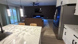 Uma cozinha moderna com bancada de mármore, forno embutido e geladeira.
