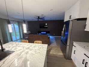Eine moderne Küche mit Marmorarbeitsplatte, einem eingebauten Ofen und einem Kühlschrank.