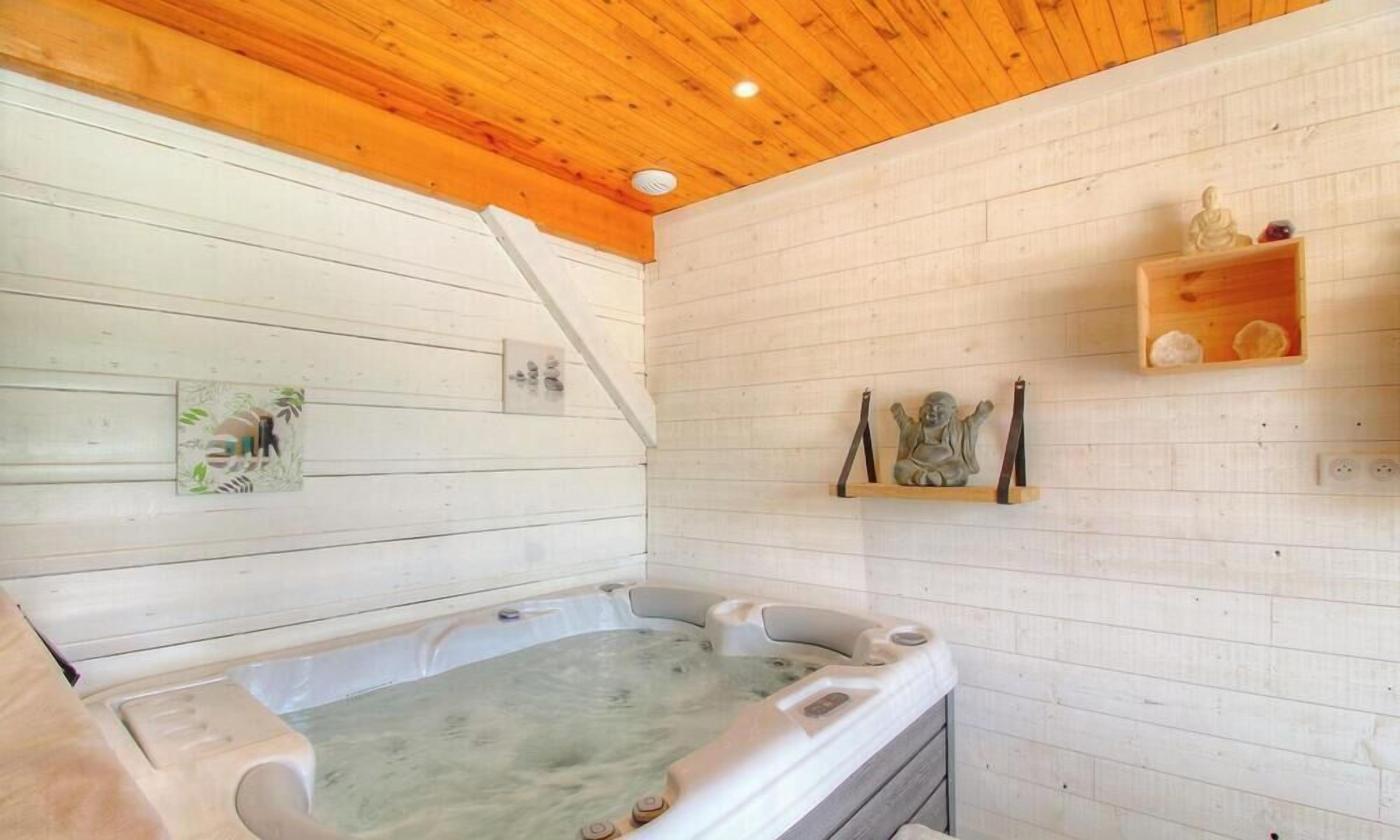 A wooden ceiling, a hot tub, and a shelf with decorative items.