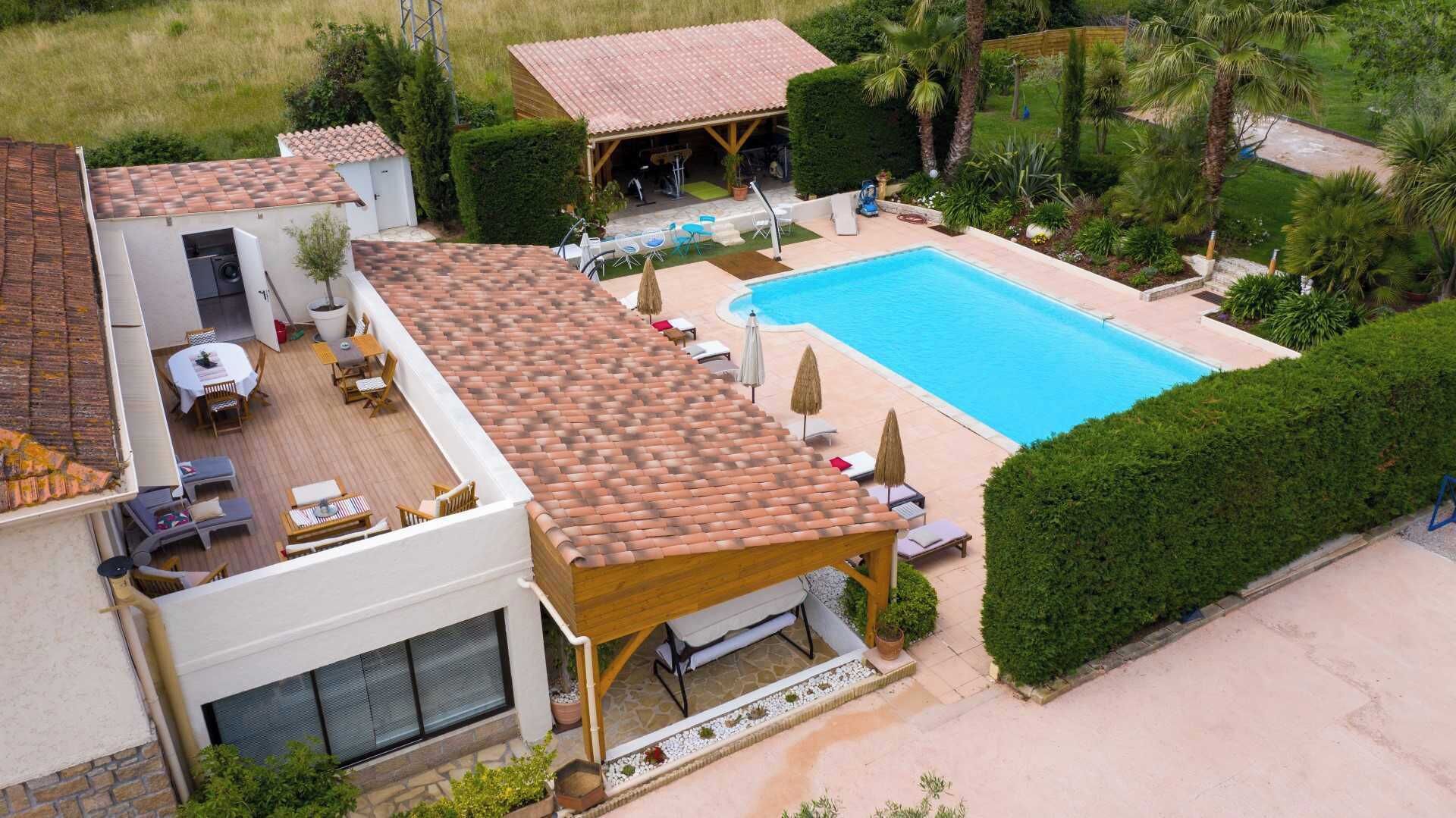 Propiedad residencial con piscina, mobiliario exterior y terraza cubierta.