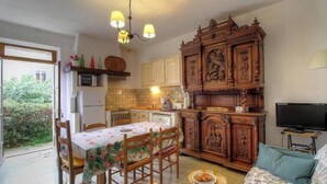 Une cuisine de taille réduite avec un coin repas, un téléviseur et un grand meuble en bois.