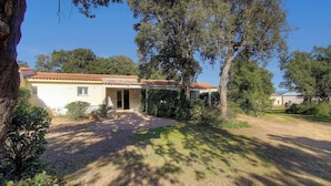 Une maison avec un toit en tuiles, une allée en gravier et de la verdure tout autour.
