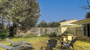 Un jardin avec une terrasse, du mobilier d’extérieur et une clôture en bois.