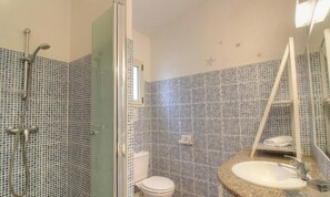 Ein Badezimmer mit Dusche, Toilette, Waschbecken und Spiegel.