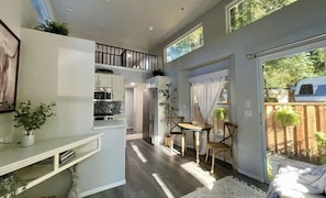 A compact kitchen with modern appliances, a dining area with a table and chairs, and a balcony with a view of the surrounding area.